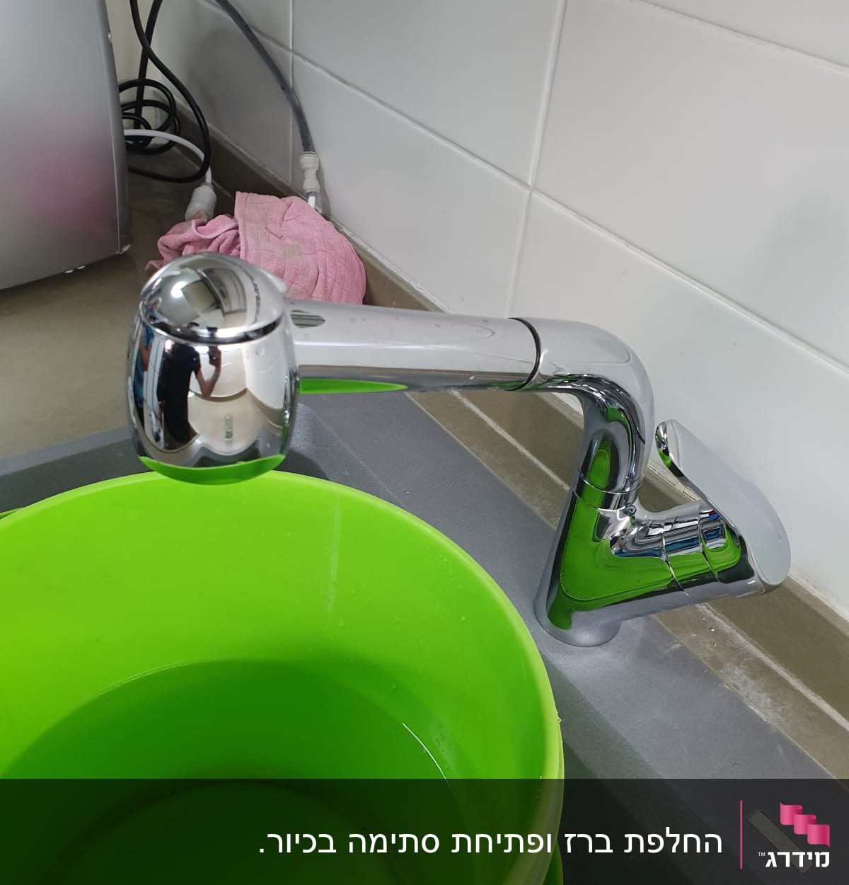 ברז מטבח עם דלי ירוק מלא במים